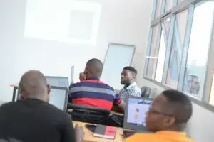 Grupo de ingenieros participando en una sesión de capacitación de ProtaStructure en un aula luminosa, usando laptops y enfocándose en una pantalla de proyección.